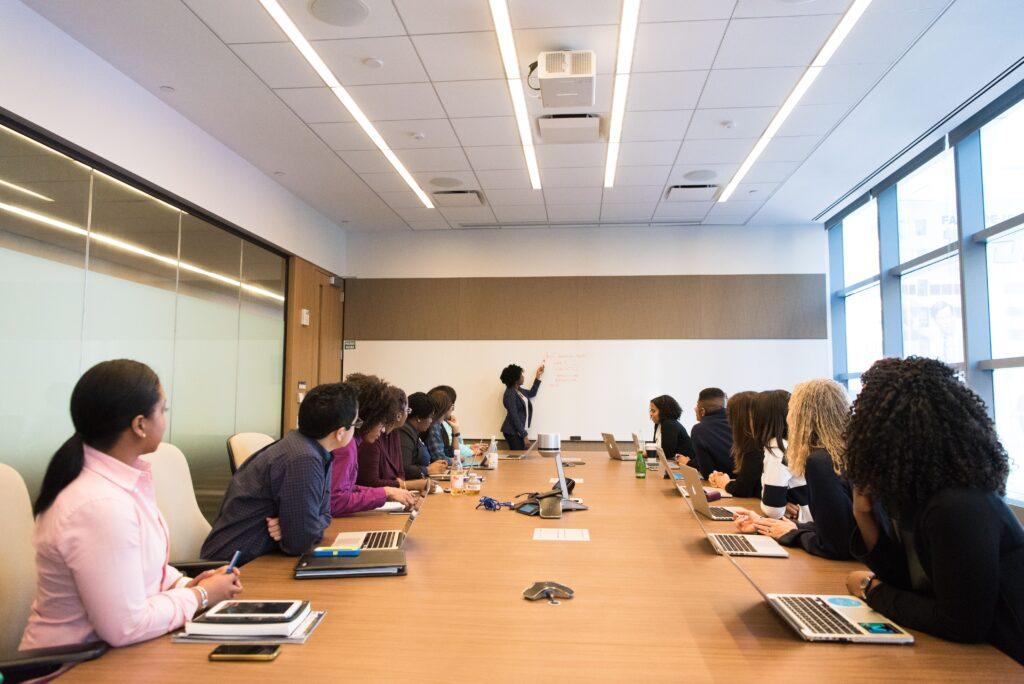Healthcare leaders in a modern conference room attentively listening to a presenter, illustrating collaboration and strategic planning for improved healthcare management.