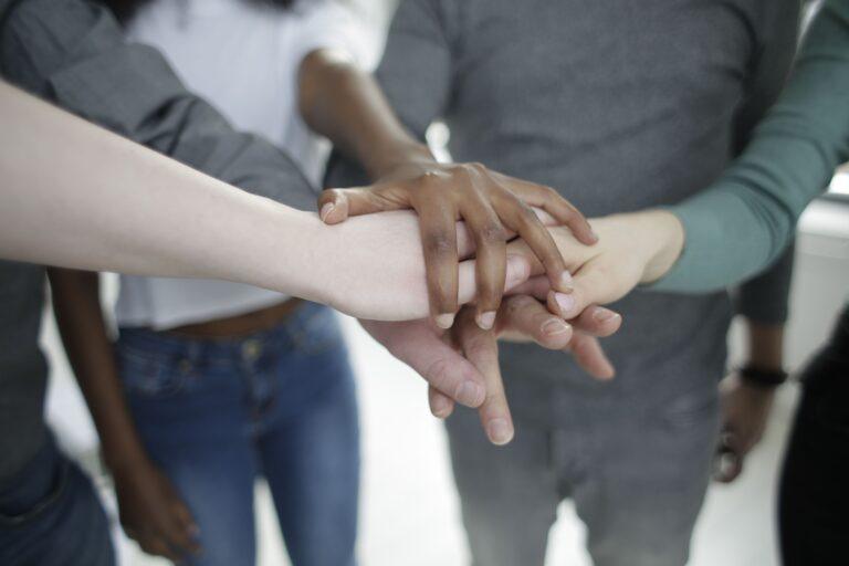 Diverse group of people stacking hands together in a gesture of unity and support